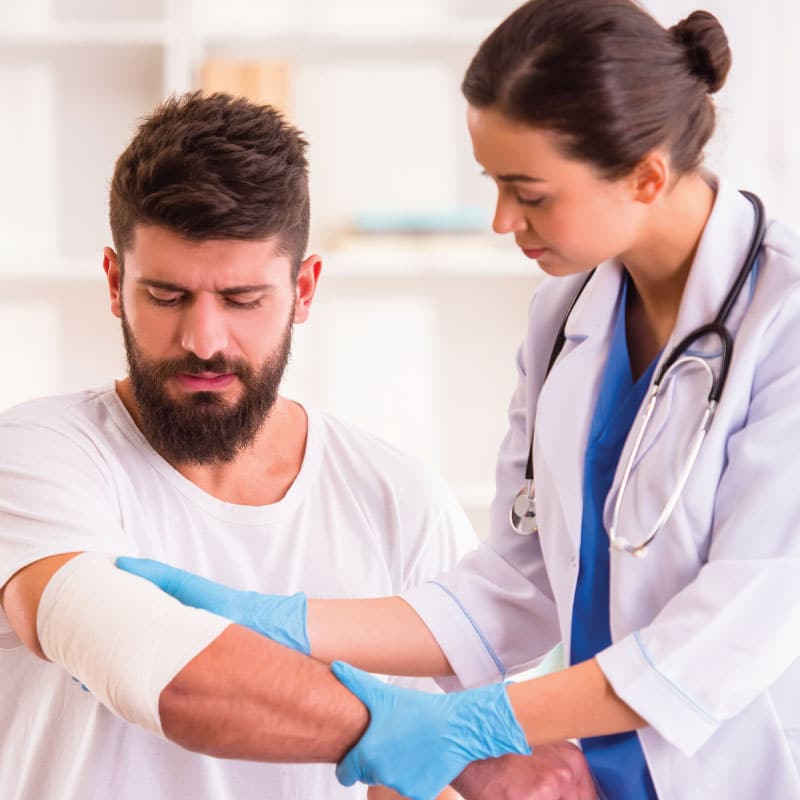 a medical provider looks at an injury to a man's arm