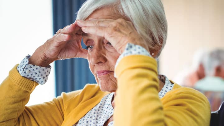 an older lady seems distraught as she sits in a nursing home