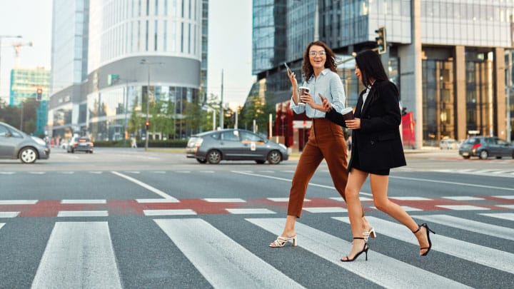 two female pedestrians cross the street in a city at a crosswalk