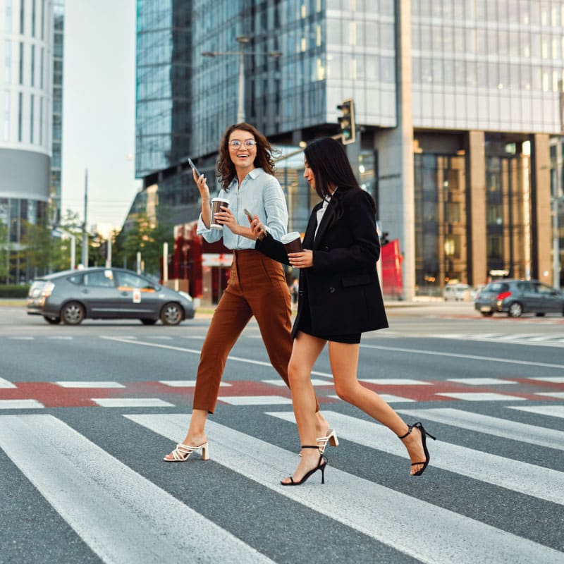 two female pedestrians cross the street in a city at a crosswalk