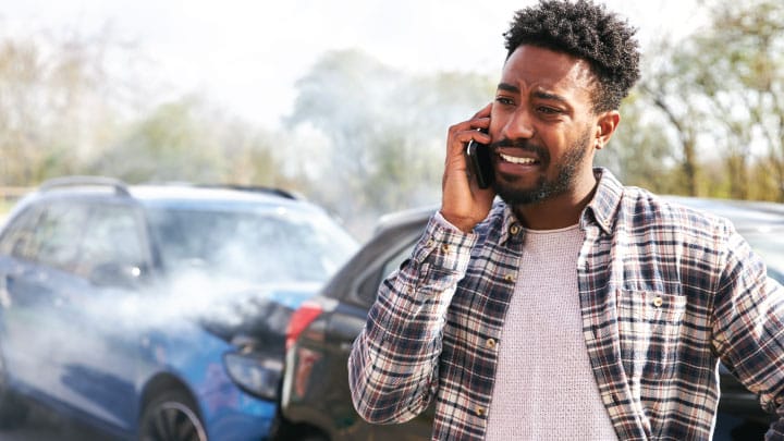 Man is distraught while speaking on the phone after an auto accident