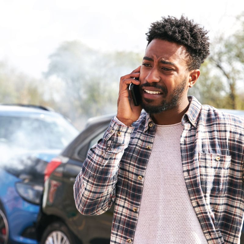 Man is distraught while speaking on the phone after an auto accident