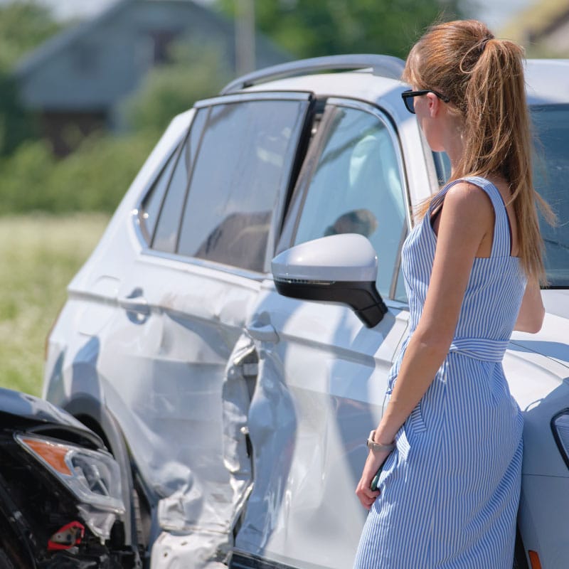 Woman surveys damage to her vehicle after auto accident